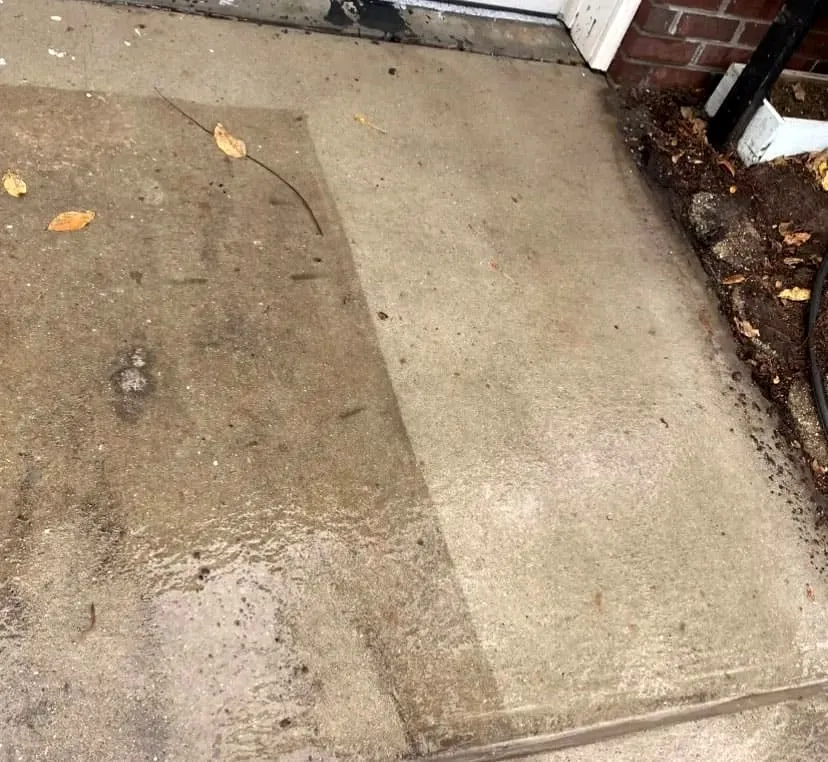 Concrete entryway mid-clean: the washed strip sits several shades lighter than the untouched slab beside it